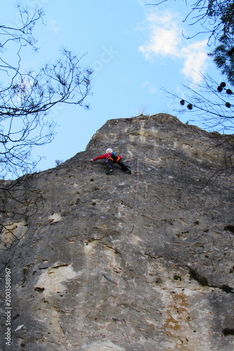 Rock climber ascending limestone cliff in natural climbing area near Cuenca, Spain.