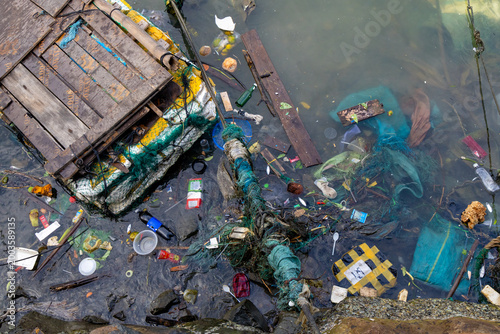 Photos Plastic waste and debris float in the water near a wooden structure in  Fishing port Vinh Truong, Nha Trang, Vietnam