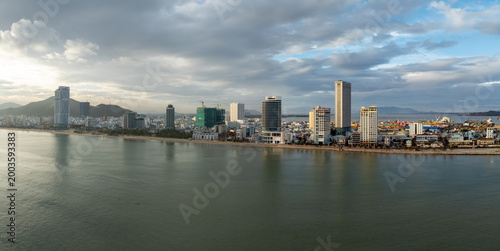 Vászonkép A panoramic view of the coastline in Quy Nhon, Binh Dinh, Vietnam, showcasing modern high-rise buildings along the sandy beach and the blue sea under a cloudy sky