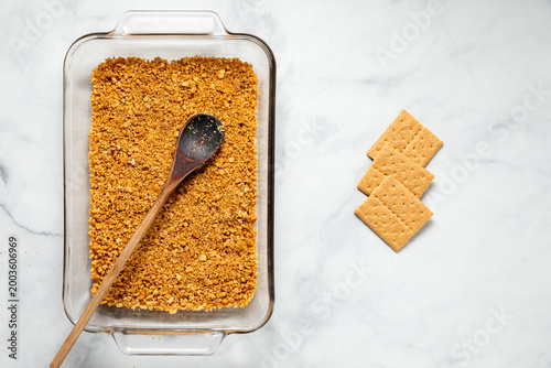 A glass baking dish filled with crushed graham crackers for a layered dessert.