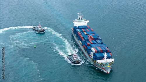 Foto two tugboats assisting and guiding a large cargo container ship in the ocean
