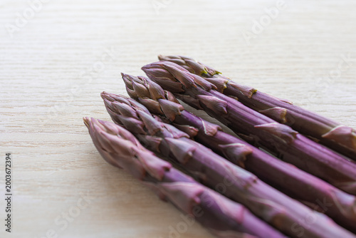 фотографія Fresh raw purple asparagus spears diagonally aligned on a wooden table