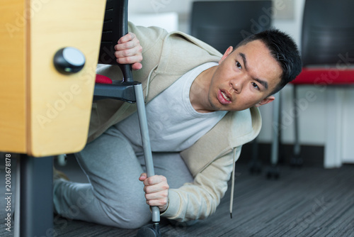 Tableau sur toile An Asian young man hides under a desk active shooter drill in a classroom, perfect for school safety, emergency preparedness, or campus security concepts