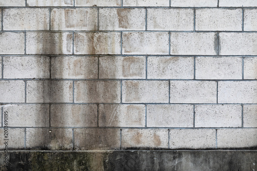 Fotografie Light grey concrete block wall with dark vertical moisture stains