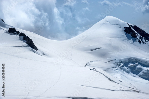 Photos Snow Covered Alpine Peak with Glacier Crevasses and Dramatic Cloudy Sky Spaghett