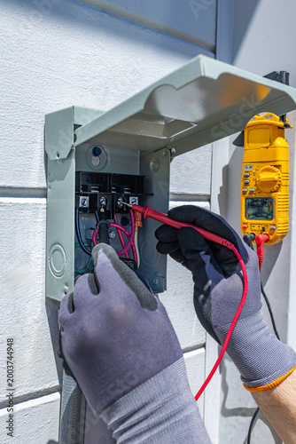Tablou pe pânză Electrician testing voltage in an outdoor 60 amp A/C electrical disconnect box w