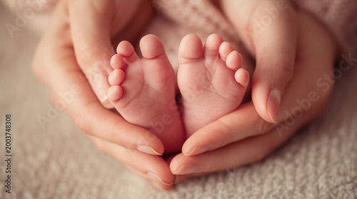 Newborn baby feet cradled in parent hands on soft blanket with tender family care