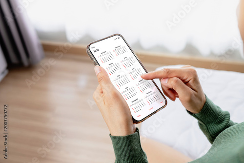 Woman checking calendar on smartphone while at home. Digital planning, schedule management, time organization and productivity lifestyle concept