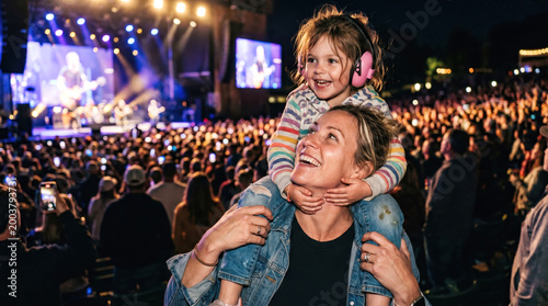 Mother and little girl with ear protection at outdoor music concert