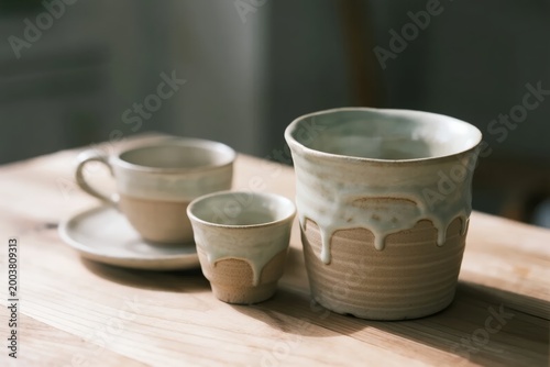 Handcrafted ceramic cups and pitcher with glazed finish on wooden table