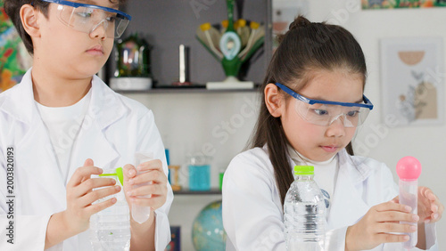 Bild auf Leinwand Two Asian Students in Lab Coats Conducting a Bernoulli Principle Science Experim