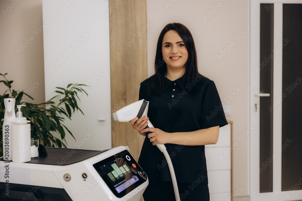 Ταπετσαρία Female cosmetologist holding laser hair removal machine smiling