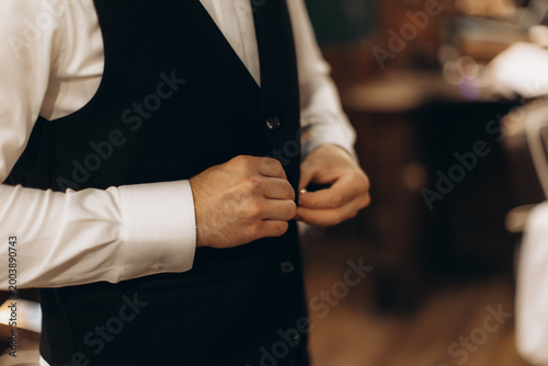Bild auf Leinwand Groom getting ready buttoning up his suit vest