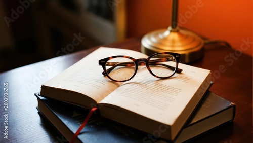 An open book with tortoiseshell glasses under warm light, creating a serene and healing reading atmosphere, making it a visual material image suitable for lifestyle and literary scenarios.
