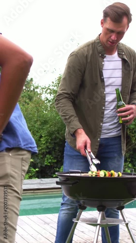 Vertical video: Approaching guest with plate asking griller checking skewers by pool, grill