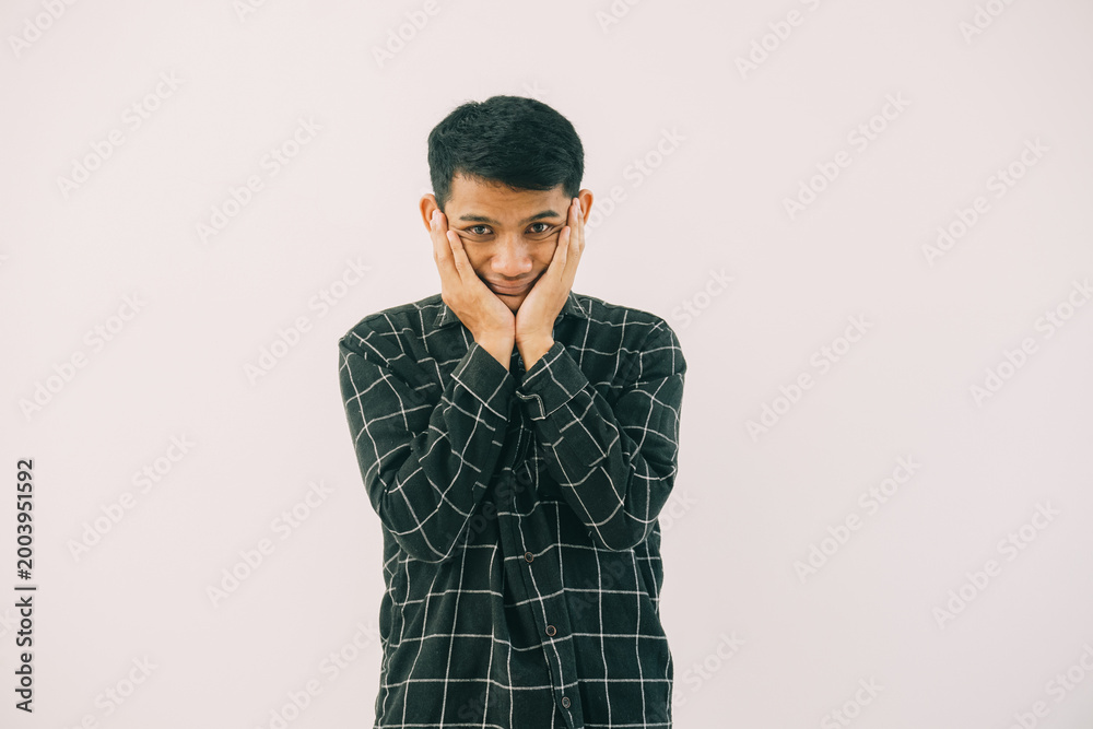 Fototapeta premium a man wearing a black and white checkered shirt with a concerned expression. he is standing alone in a plain white setting.