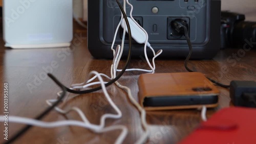 Messy cables on floor connected to portable power station before full setup with slight zoom. Concept of energy management, electricity backup and home office power usage.