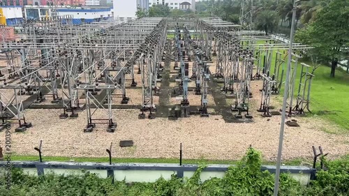 A high-voltage electrical transformer station situated near an expanding city in India, showcasing critical grid infrastructure and electrical distribution technology.