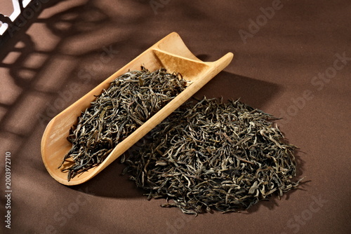 Fotografía Bamboo tea scoop holding loose-leaf green tea on a brown fabric surface