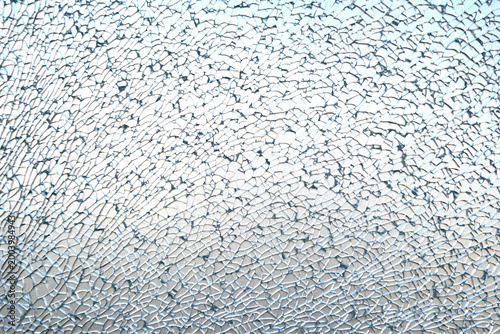 A close-up texture of completely shattered tempered glass, displaying an intricate web of tiny fragments.