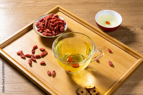 Fotografie Premium dried goji berries in a small ceramic bowl on a wooden tray with sliced