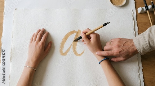 Child learning calligraphy with parent guidance on handmade paper