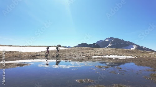 Couple Walking Near Water Reflection in Mountain Landscape