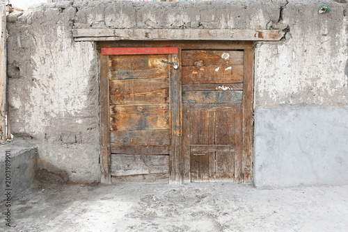 A rustic double wooden door built into a textured, aging concrete wall
