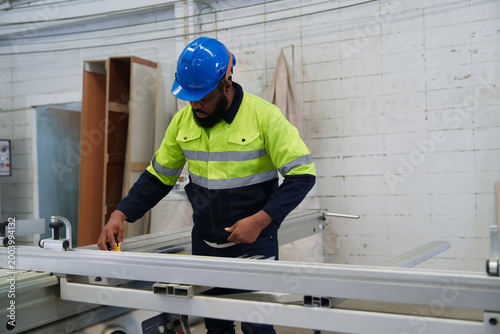 Valokuva High-Visibility Worker Measuring Wooden Board with Yellow Measuring Tool in Brig