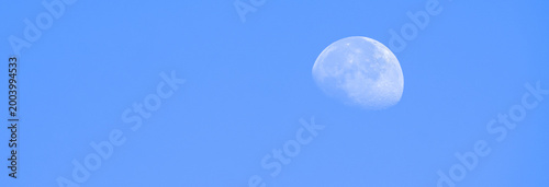 Photography The moon visible in a bright daytime sky, creating a serene celestial contrast and highlighting nature’s subtle beauty during daylight hours