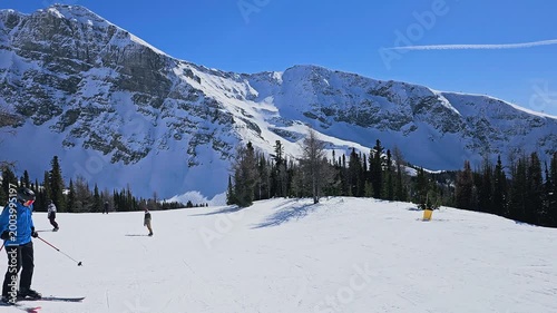 Chamonix, France winter ski scene with skiers carving downhill below towering Alps peaks and expansive snowy resort terrain.