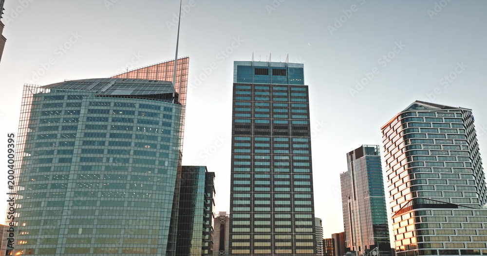 Obraz premium Sydney skyscrapers in central business district reflecting warm sunset light, showcasing modern architecture and urban development against clear sky, symbolizing business and finance. Aerial panorama