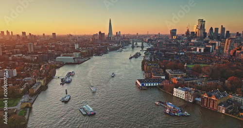 Foto London cityscape panoramic aerial view, modern skyline at sunset, The Shard and Tower Bridge, boats navigate River Thames under bright colorful evening sky