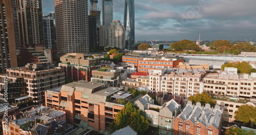 Australia, Sydney City: modern downtown skyscrapers and historic low-rises buildings houses under bright cloudy sky, highlighting urban development. Drone flight aerial view