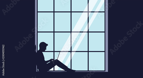 Silhouette of a man sitting on a large window ledge working on his laptop during the night with bright light reflecting off the glass.