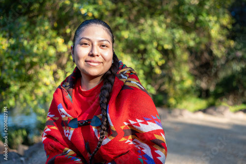 Peruvian woman wearing a traditional patterned poncho, smiling at the camera outdoors