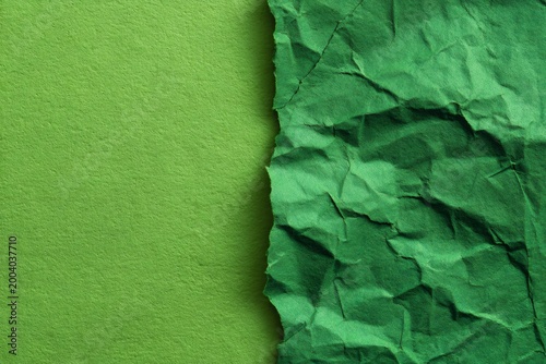 Smooth light green paper separated by a torn edge from darker, heavily crumpled green paper, creating a textural contrast