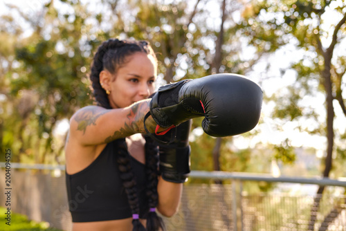 Fotografie Latina woman training boxing outdoors practicing punches