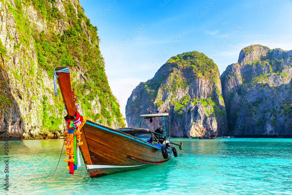 Fototapeta premium Longtail Boat in Maya Bay Lagoon, Phi Phi islands in Thailand. Tropical scenery of Maya Bay with traditional longtail boat, turquoise water and dramatic limestone cliffs