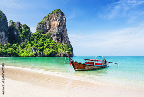 Traditional longtail boat and turquoise water on Railay Beach in Krabi, Thailand. Scenic Railay Beach with traditional boats, turquoise water and limestone cliffs.