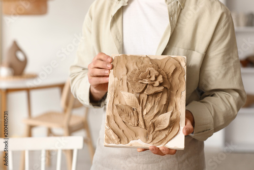 Schilderij op canvas Young male sculptor with clay figure in workshop, closeup