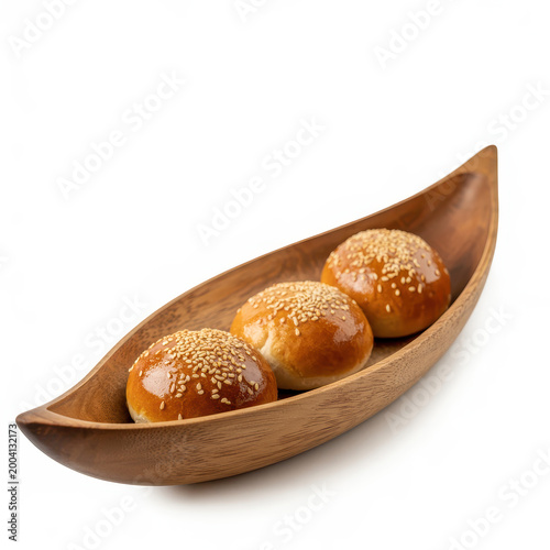 Three golden brown bread rolls topped with sesame seeds in a wooden boat shaped bowl