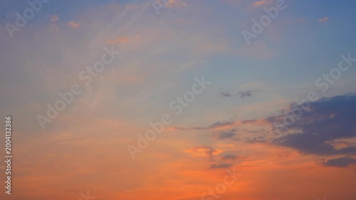 A sunset sky timelapse video footage featuring thin cirrus and scattered stratocumulus clouds glowing in warm orange tones, capturing smooth gradients, soft motion and atmospheric transitions at dusk.