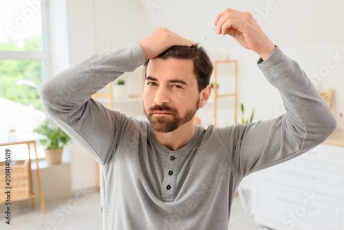 Man using serum for hair gr...