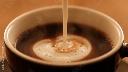 Latte coffee with milk pouring and smooth foam swirl creating latte art top view close up