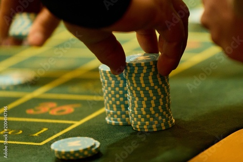 Close Up of Hand Placing Casino Chips on Green Gambling Table
