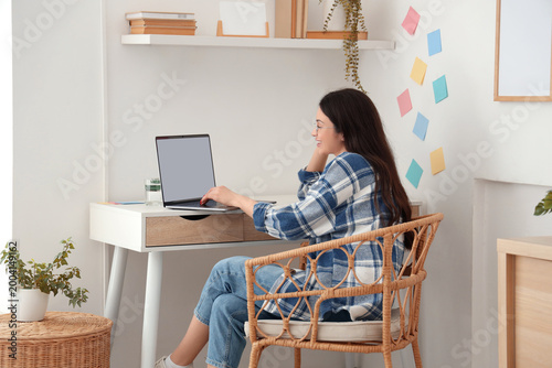 Tableau sur toile Young woman working with blank laptop at table in office