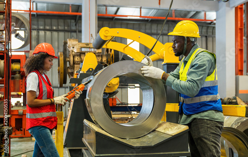 The foreman and workers in the metal sheet factory are operating the machinery.