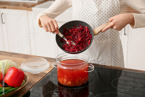 Young woman adding frying v...