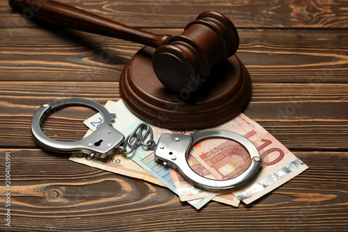 Obraz na płótnie Handcuffs with judge's gavel and euro banknotes on wooden background, closeup